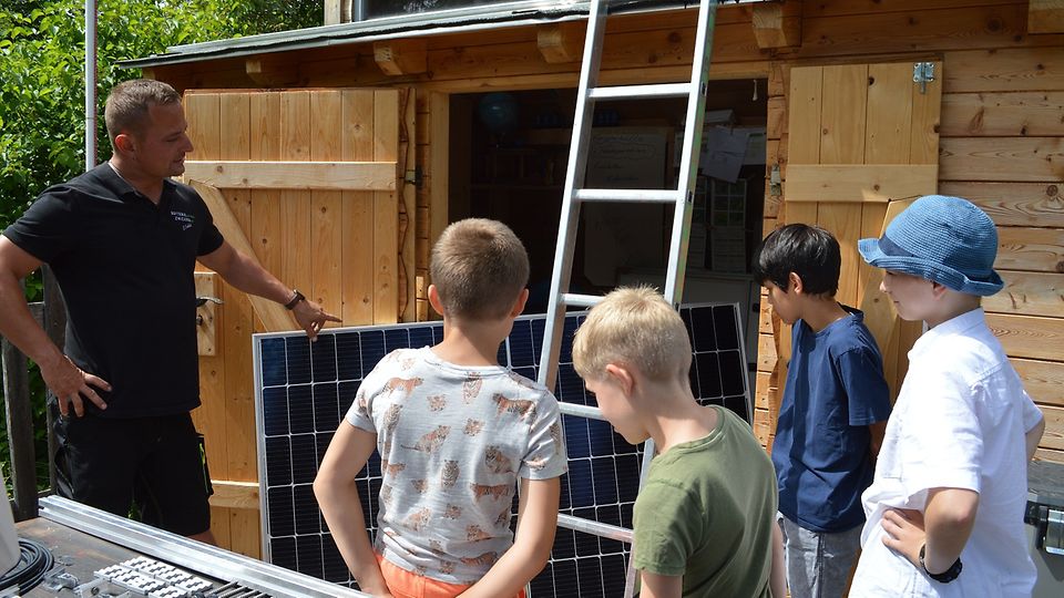 67611_KD_Sachsen_Christoph Fröhlich erklärt den Kindern das Solarpaneel und dessen Verwendung.jpg