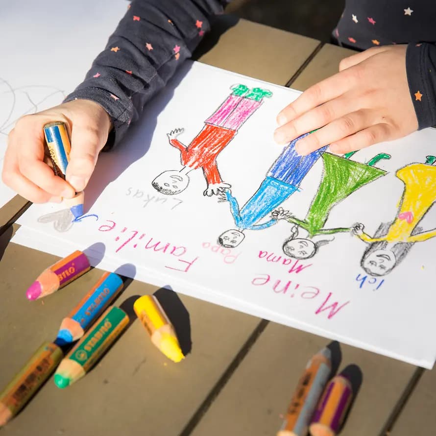 Ein Kind malt eine Familie mit Buntstiften