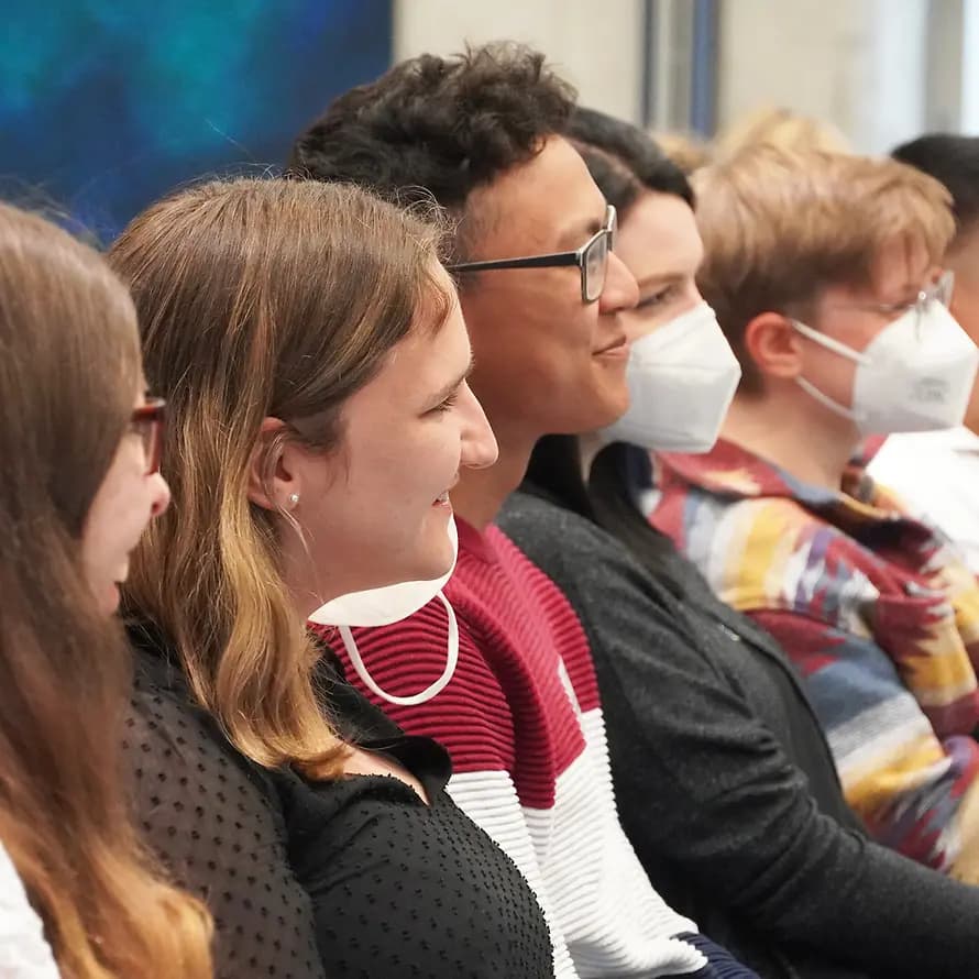 Rückblick Transferkonferenz AGJ Eine Gruppe weiblicher und männlicher junger Erwachsener sitzt lächelnd in einer Reihe