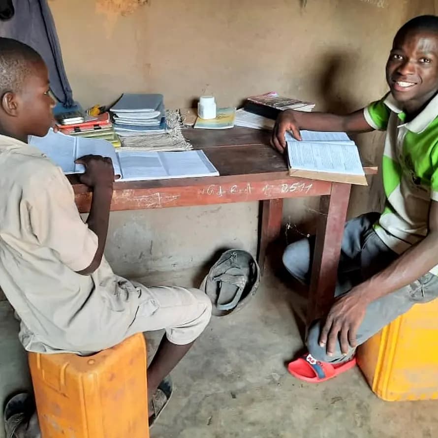 Yédés Söhne gehen zur Schule Zwei Brüder in Afrika mit aufgeklappten Schulheften
