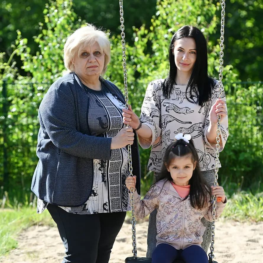 73624_SOS-MZ-Salzgitter_Ukraine-Hilfe_16052022_FrankMay_6286.jpg Großmutter Iryna und Mutter Ilona stehen neben Milena, die auf einer Schaukel sitzt.