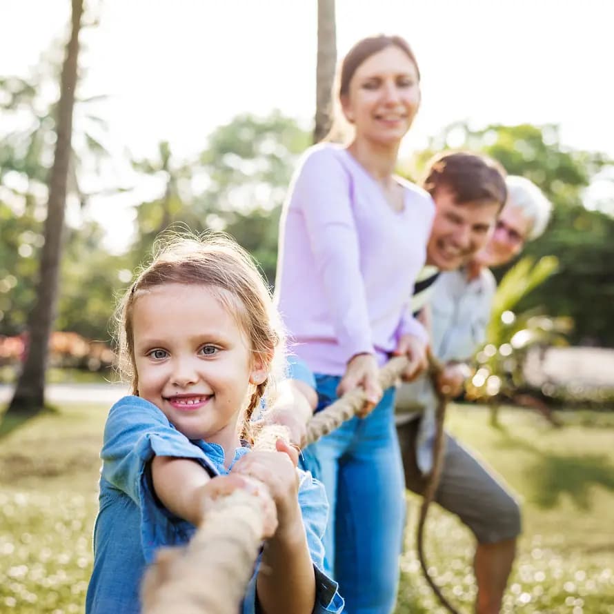 42038_shutterstock_Rawpixel_1115130767.jpg Mädchen im Vordergrund, das mit ihrer Familie an einem Seil zieht