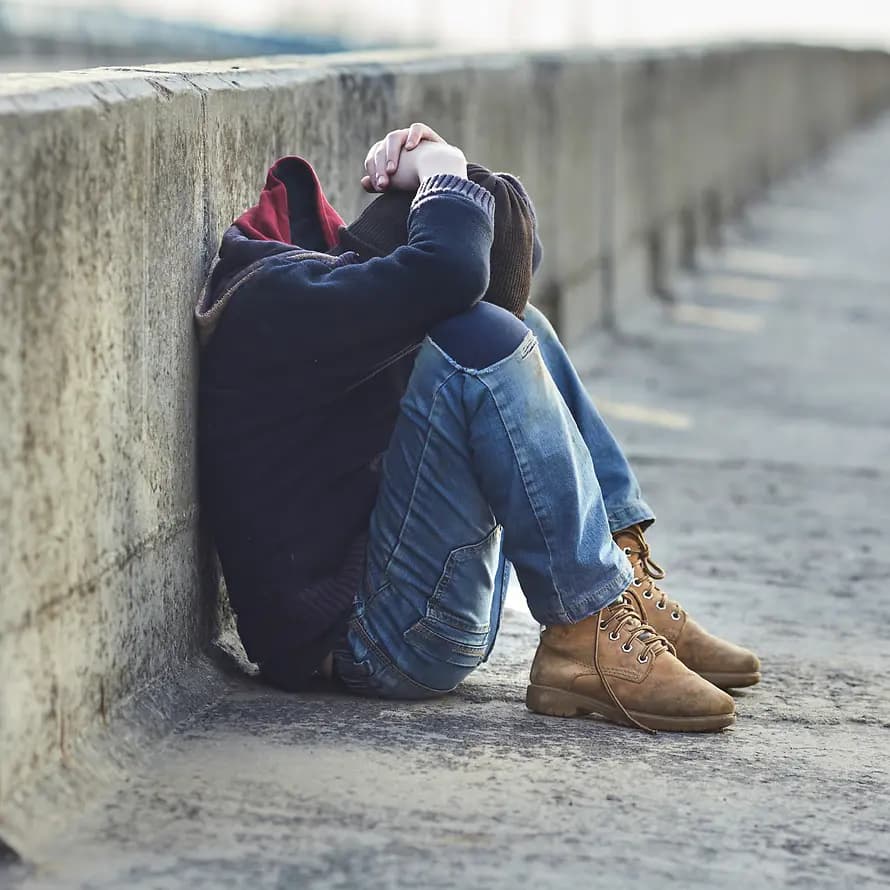 Not wohnungsloser junger Menschen steigt Junge sitzt mit gesenktem Kopf an einer Wand gelehnt auf der Straße