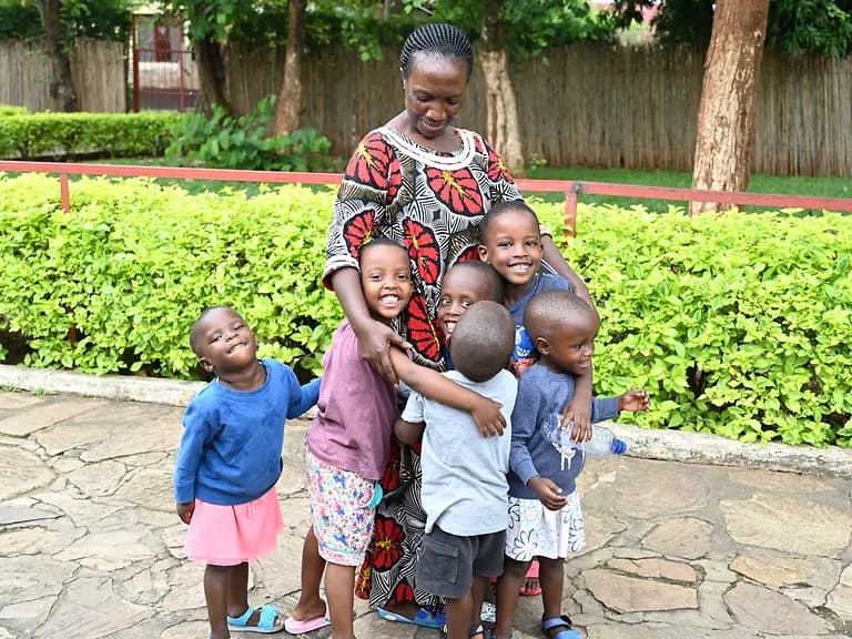 SOS-Kinderdorfmutter im SOS-Kinderdorf Bujumbura umarmt Kinder