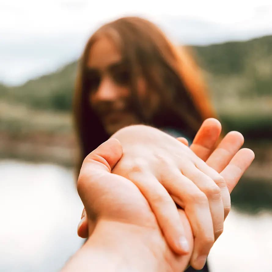 Lächelndes Mädchen ergreift eine sich entgegenstreckende Hand