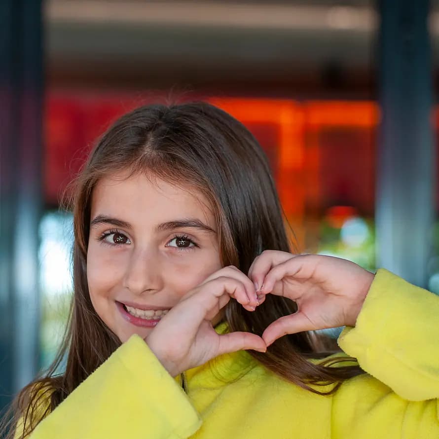 96690_SOS-KD_iStock_MehmetHilmiBarcin_1199586498.jpg Mädchen lacht und formt Herz mit den Händen