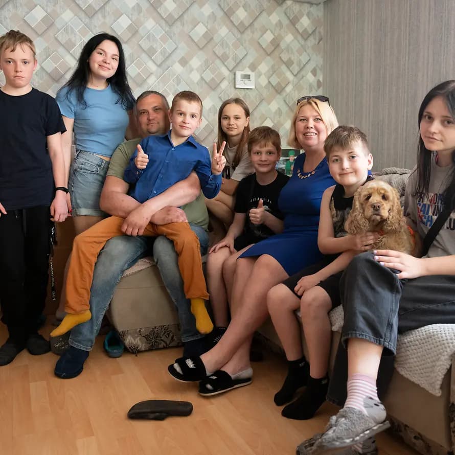 98302_SOS-Kinderdorf Ukraine_Browary_(c) Katerina Ilievska.jpg Großfamilie mit Eltern, sieben Kindern und Hund sitzt auf Sofa.