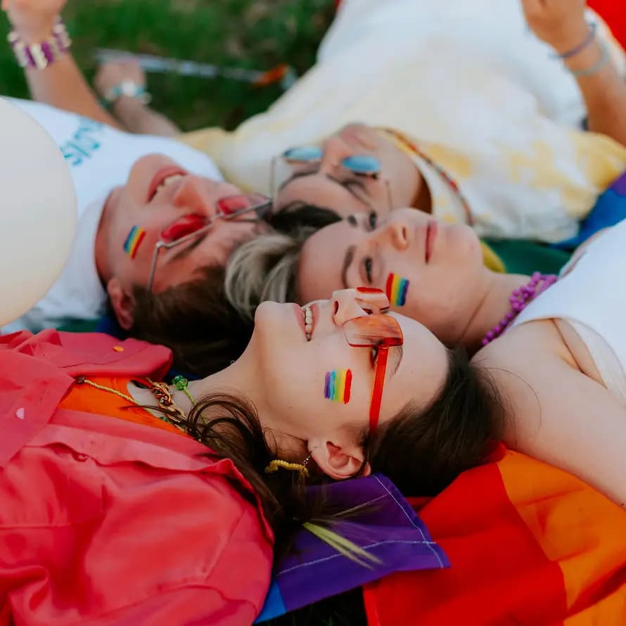 Queere Jugendliche Eine Gruppe Jugendlicher mit Regenbogensymbol liegen entspannt auf einer Wiese