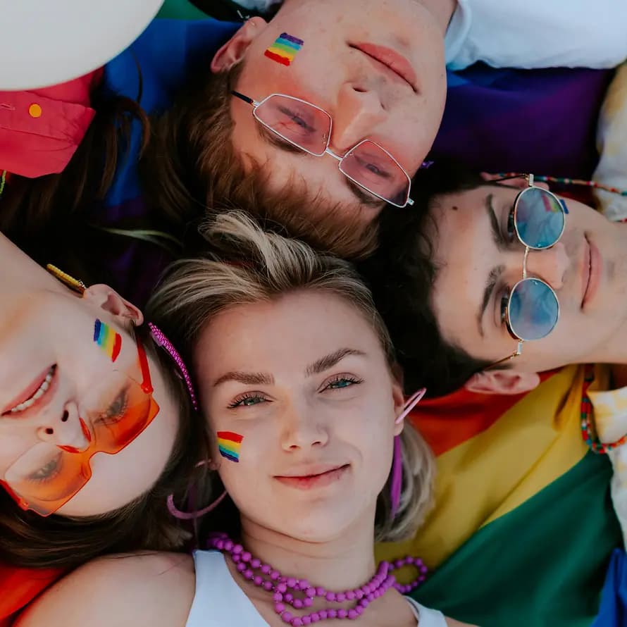 Queer sein in der Jugendhilfe Eine Gruppe Jugendlicher mit Regenbogensymbol liegen entspannt auf einer Wiese