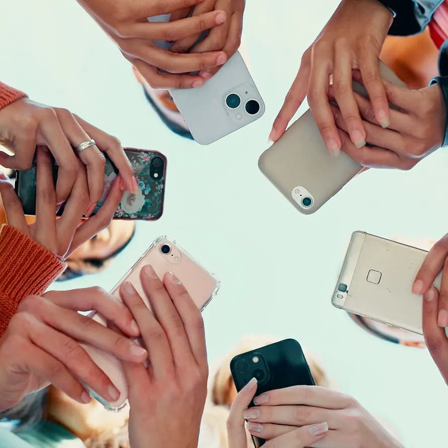 Stageteaserbild WBTs Mediennutzung Blick auf sechs Handys und die Hände von im Kreis stehenden jungen Menschen, von unten fotografiert