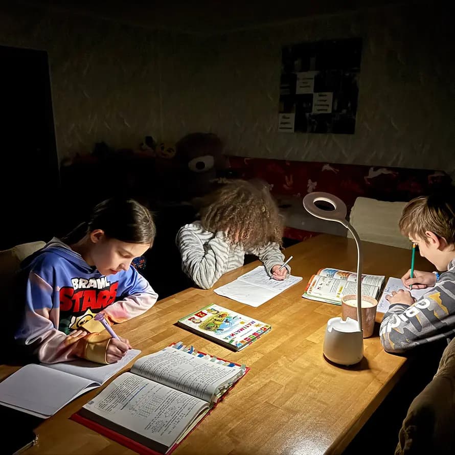 123993_SOS-Kinderdorf Ukraine_Kinder während Blackout im Kerzenlicht.jpg Kinder machen Schulaufgaben im Licht einer Taschenlampe