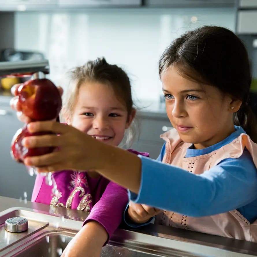 90223_SOS_KD_Dortmund_03082023_SebastianPfuetze-7023.jpg Zwei Mädchen waschen Obst unter einer Küchenspüle ab