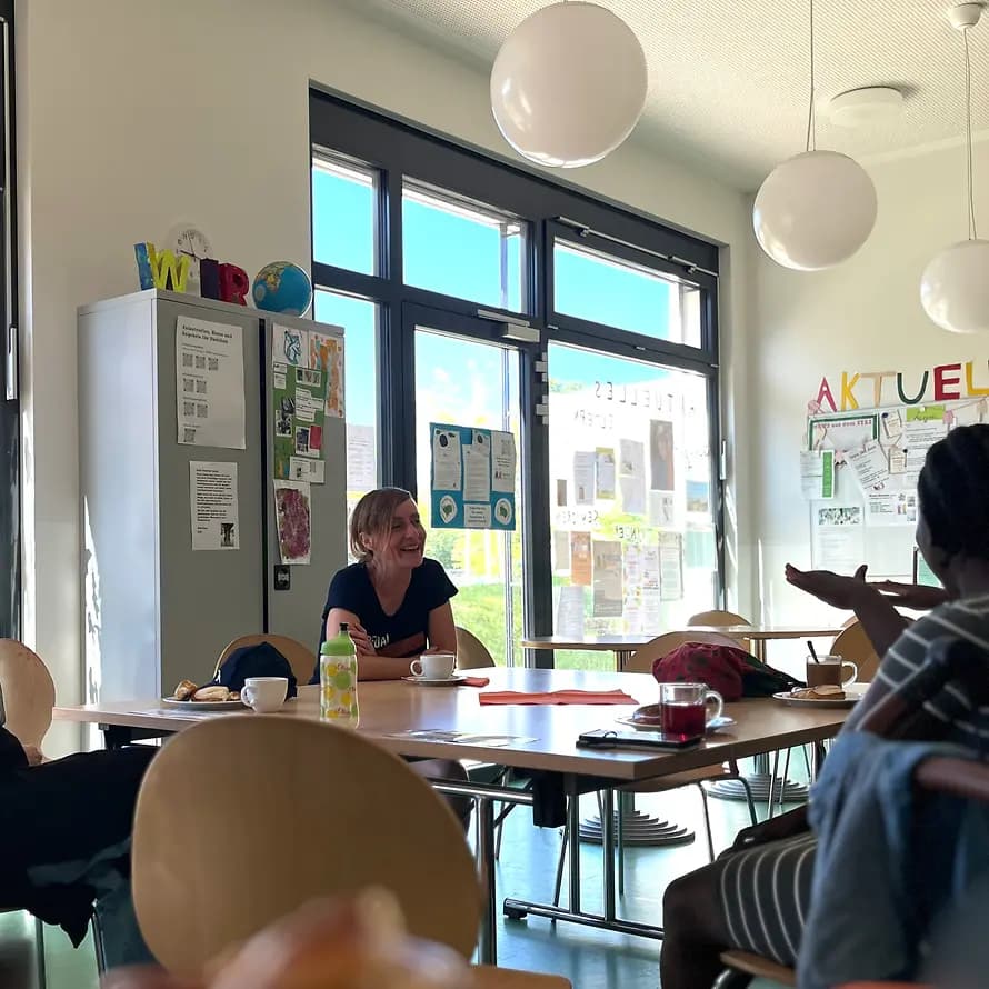 125458_Bild 2 das Elterncafé startet.jpeg Personen sitzen bei Kaffee und Tee gemeinsam an einem Tisch und unterhalten sich