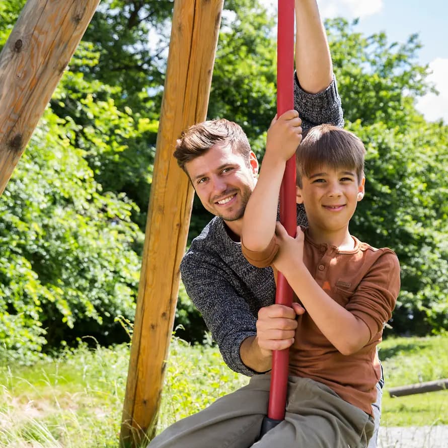 74528_SOS-KD-Wuerttemberg_Modell-Shooting_Juni2022_SebastianPfuetze-5080.jpg Erzieher hilft Kind auf Kinderseilbahn