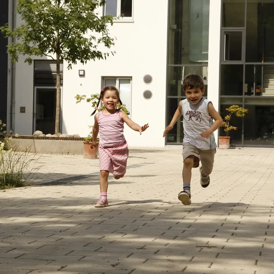 Glücklich aufwachsen: zwei Kinder laufen auf dem Gelände des SOS-Kinderdorfs Glücklich aufwachsen: zwei Kinder laufen auf dem Gelände des SOS-Kinderdorfs