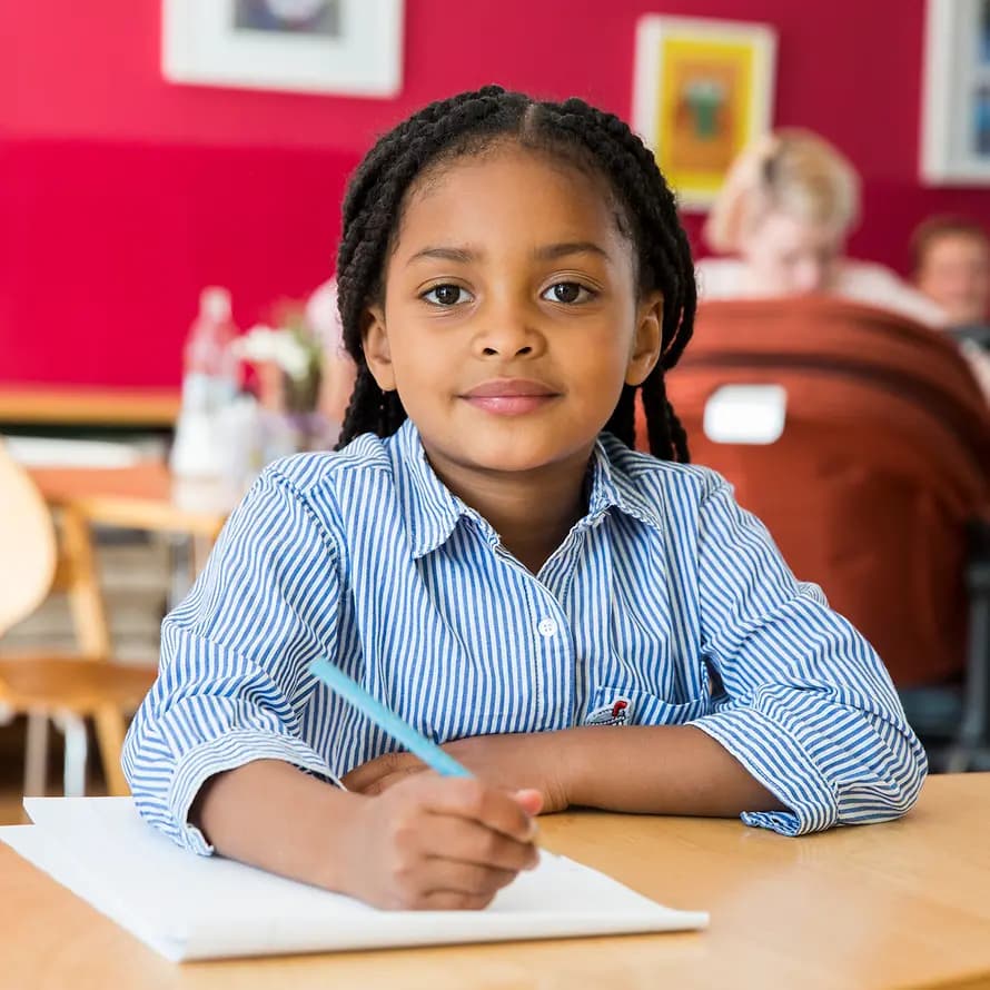 Schulsozialarbeit SOS-Kinderdorf Mädchen sitzt mit Stift und Papier am Tisch