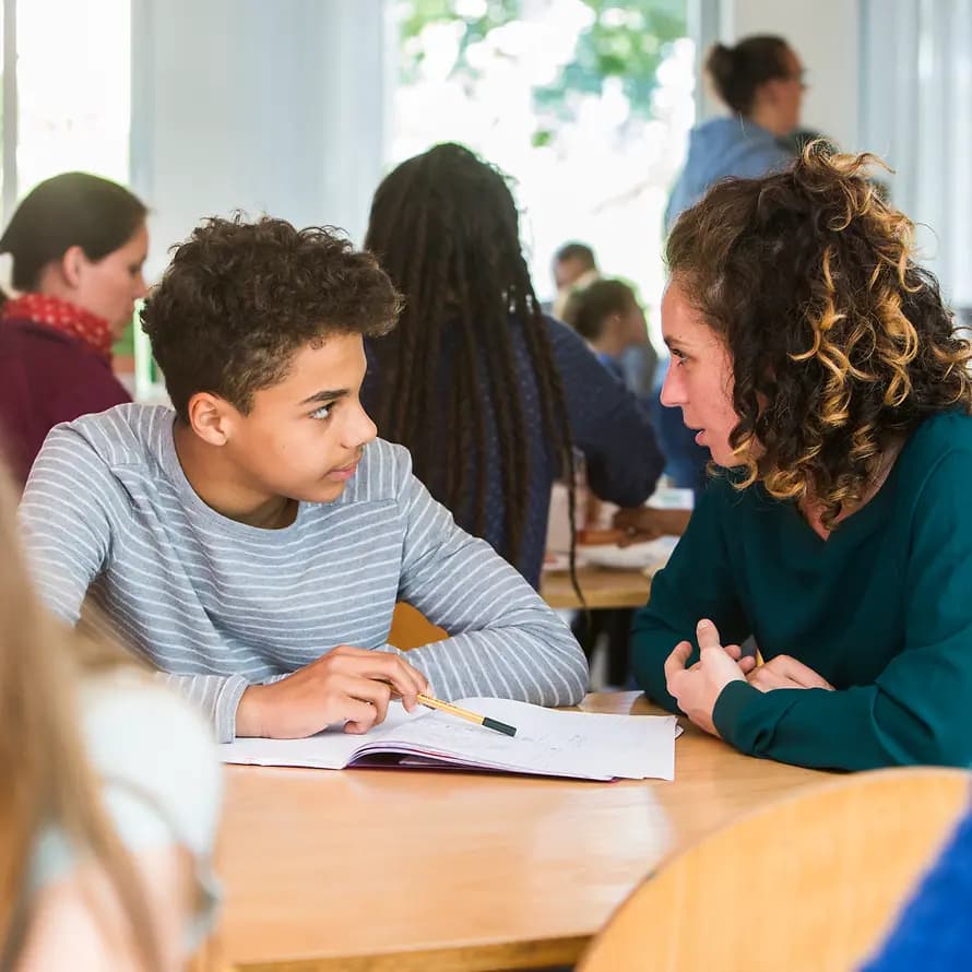 Hausaufgabenhilfe SOS-Kinderdorf Junge sitzt mit Frau an Schulaufgaben