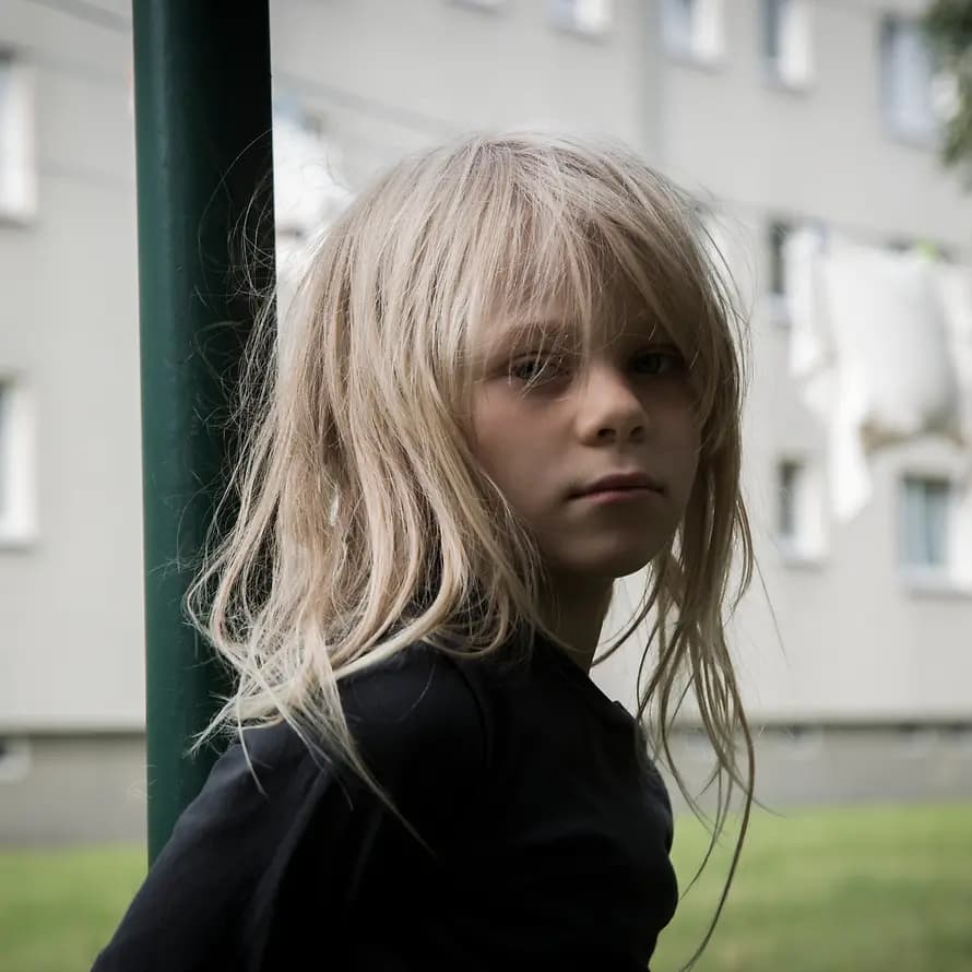 Samira SOS-Kinderdorf Blondes kleines Mädchen lehnt an Laterne