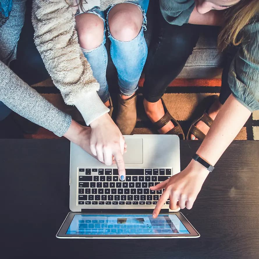 Drei junge Menschen zeigen sich gegenseitig etwas am Laptop-Bildschirm
