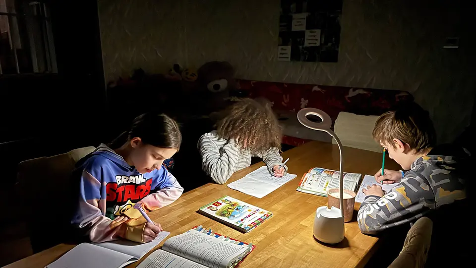 Kinder machen Schulaufgaben im Licht einer Taschenlampe